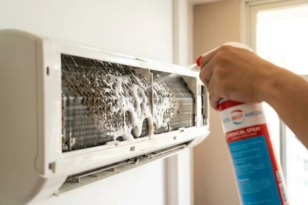 Coolbest Aircon technician spraying chemical solution on evaporator coil in Tampines HDB flat